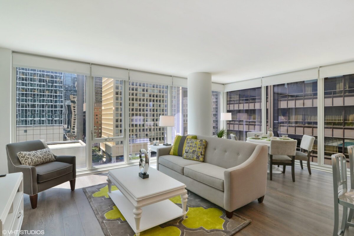 Modern high-rise apartment living room with floor-to-ceiling windows, city views, contemporary furniture, and adjacent dining area.