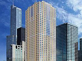 Tall modern skyscrapers with glass and concrete exteriors stand against a blue sky with scattered clouds in an urban cityscape.