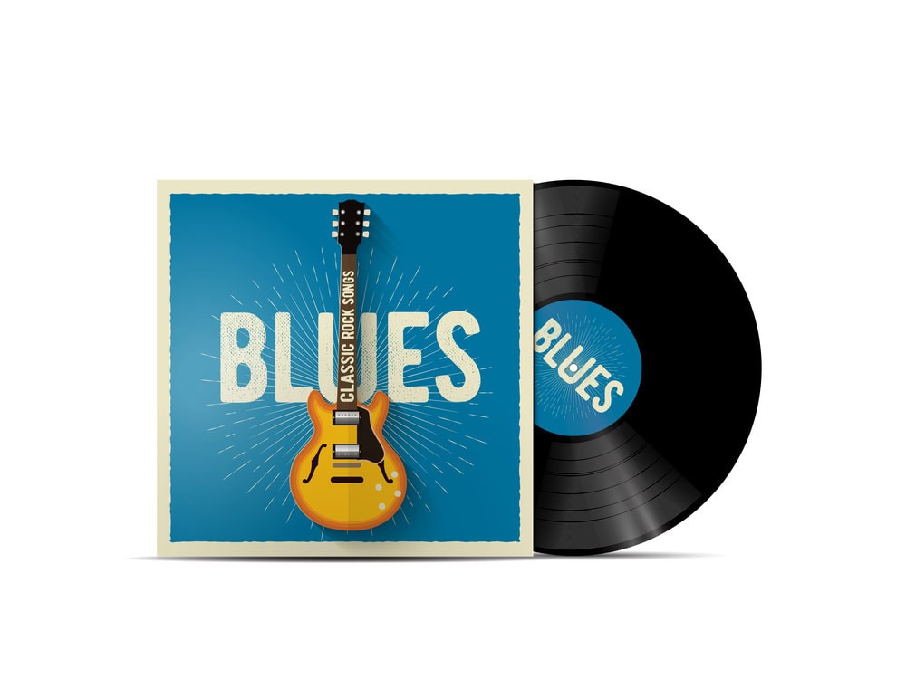 A vinyl record partially out of its sleeve labeled "BLUES," featuring a yellow electric guitar and the words "CLASSIC ROCK SONGS" on a blue background.