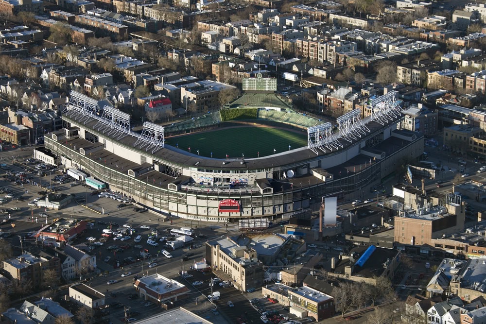 Aerial view of a large baseball stadium surrounded by city buildings and streets, with the field and empty stands visible.