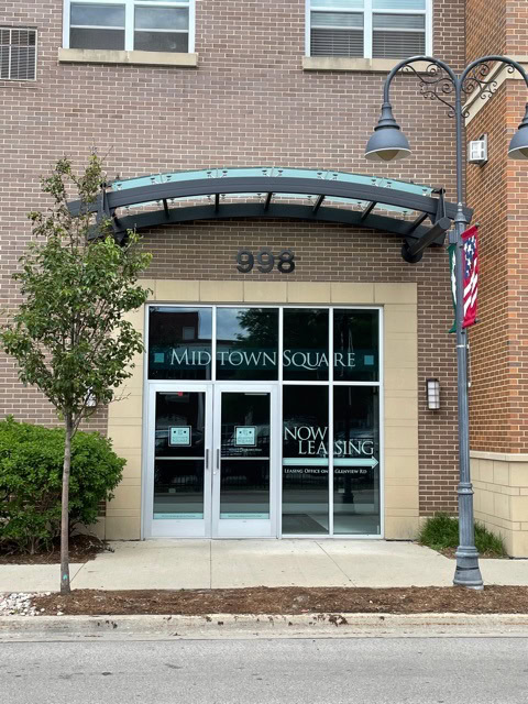 Street-level entrance of a brick building with glass doors labeled 
