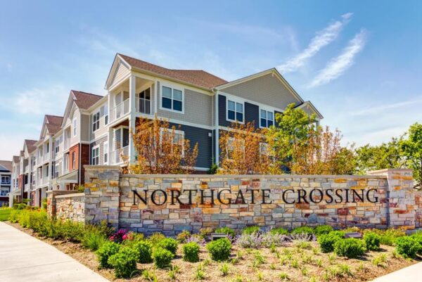 Three-story apartment buildings behind a stone wall with 