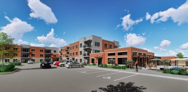 Three-story apartment complex with a parking lot in front, including accessible parking spaces, landscaping, and people walking near the entrance on a sunny day.