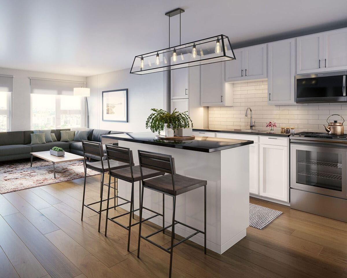 Modern kitchen with white cabinets, an island with three bar stools, stainless steel appliances, wood flooring, and a living area with a sofa in the background.