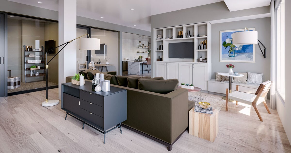 Modern living room with a green sofa, black console, floor lamps, built-in shelves, artwork, and large windows; kitchen and office visible in the background.